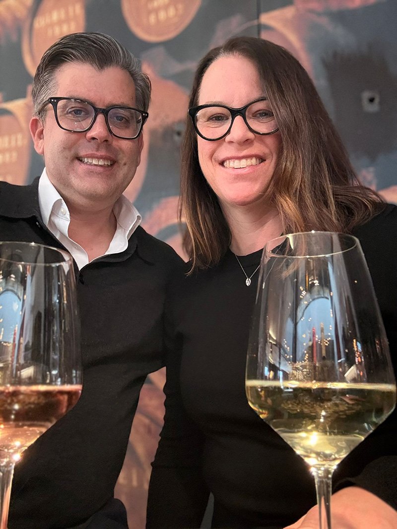 Adam and Erin toasting with wine glasses.