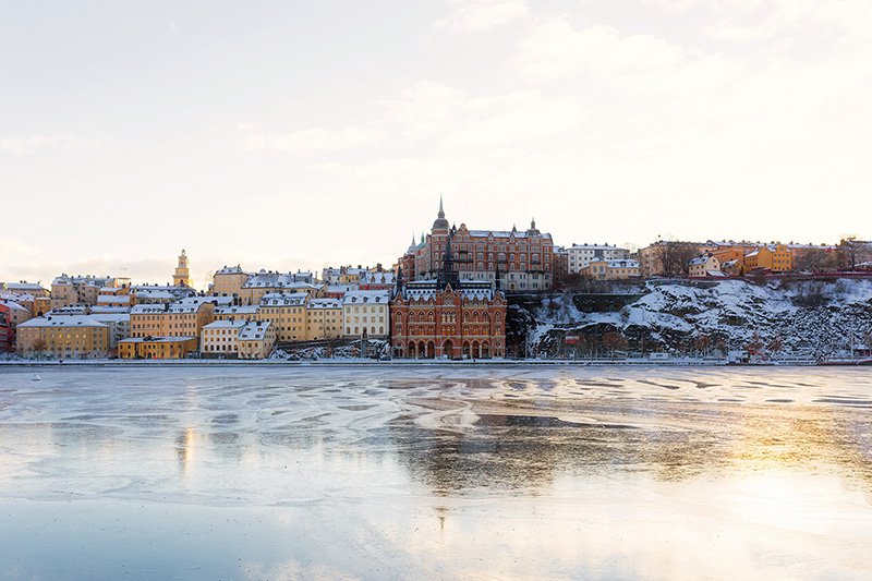 Snow covered building in Sweden with a lake in front.